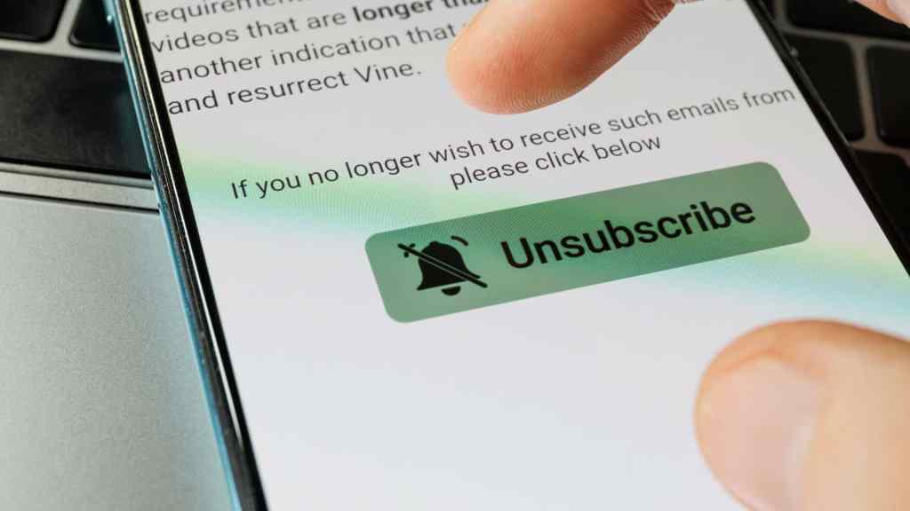 A finger hovers over a green "Unsubscribe" button on a smartphone screen displaying an email message.