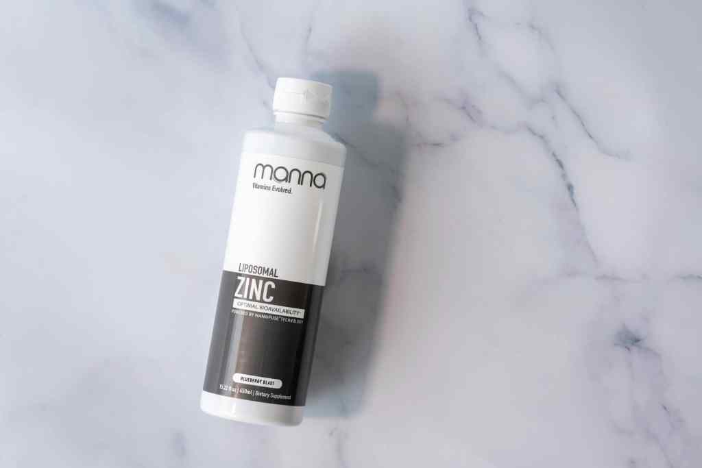 A bottle of liposomal zinc supplement with a white and black label on a marble surface.