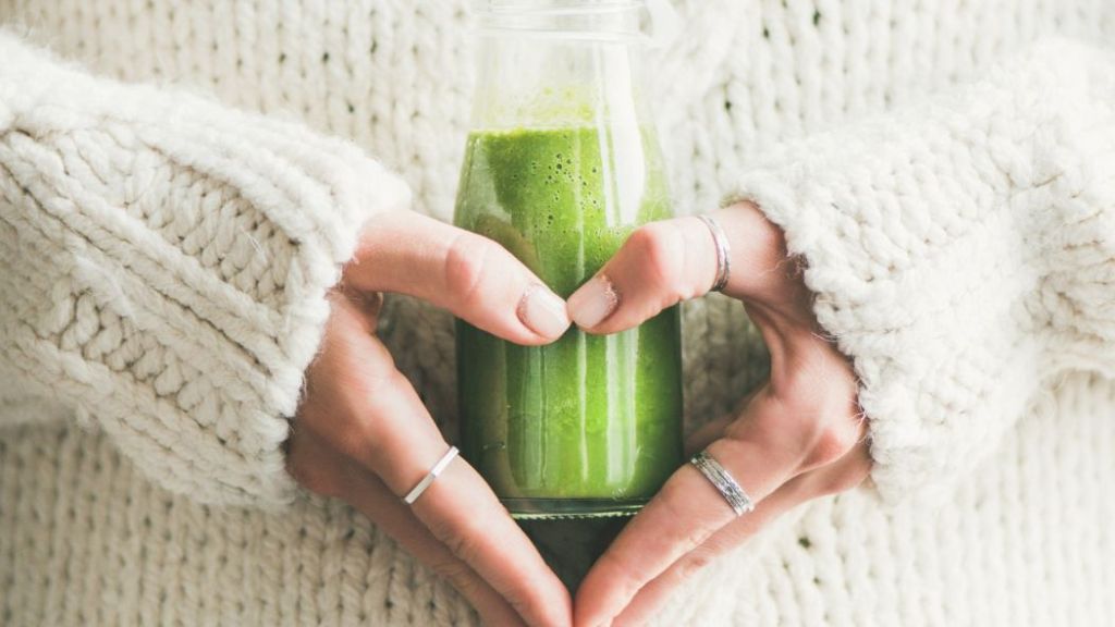 Person holding a bottle of green smoothie.
