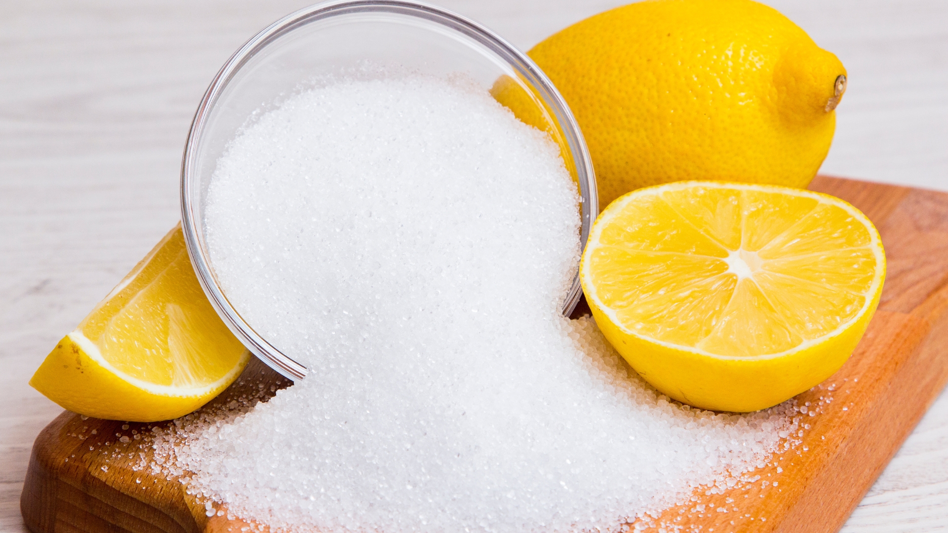 Bowl of citric acid salt poured over with lemon wedges.