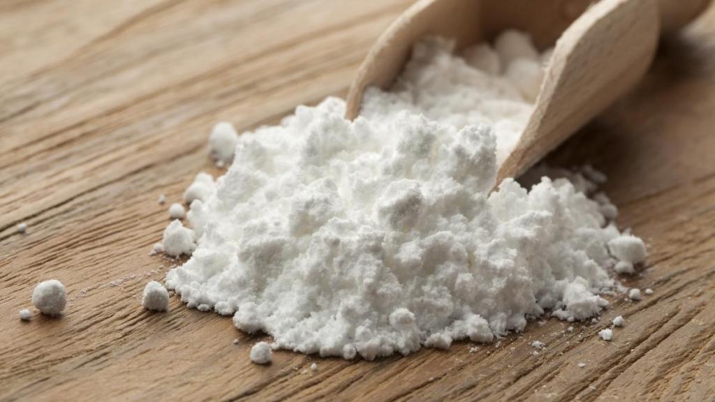 Potassium powder spilling out of a large wooden spoon.