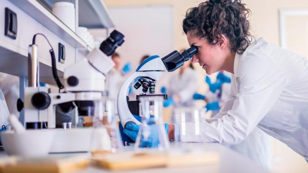 Female scientist looking through a microscope.